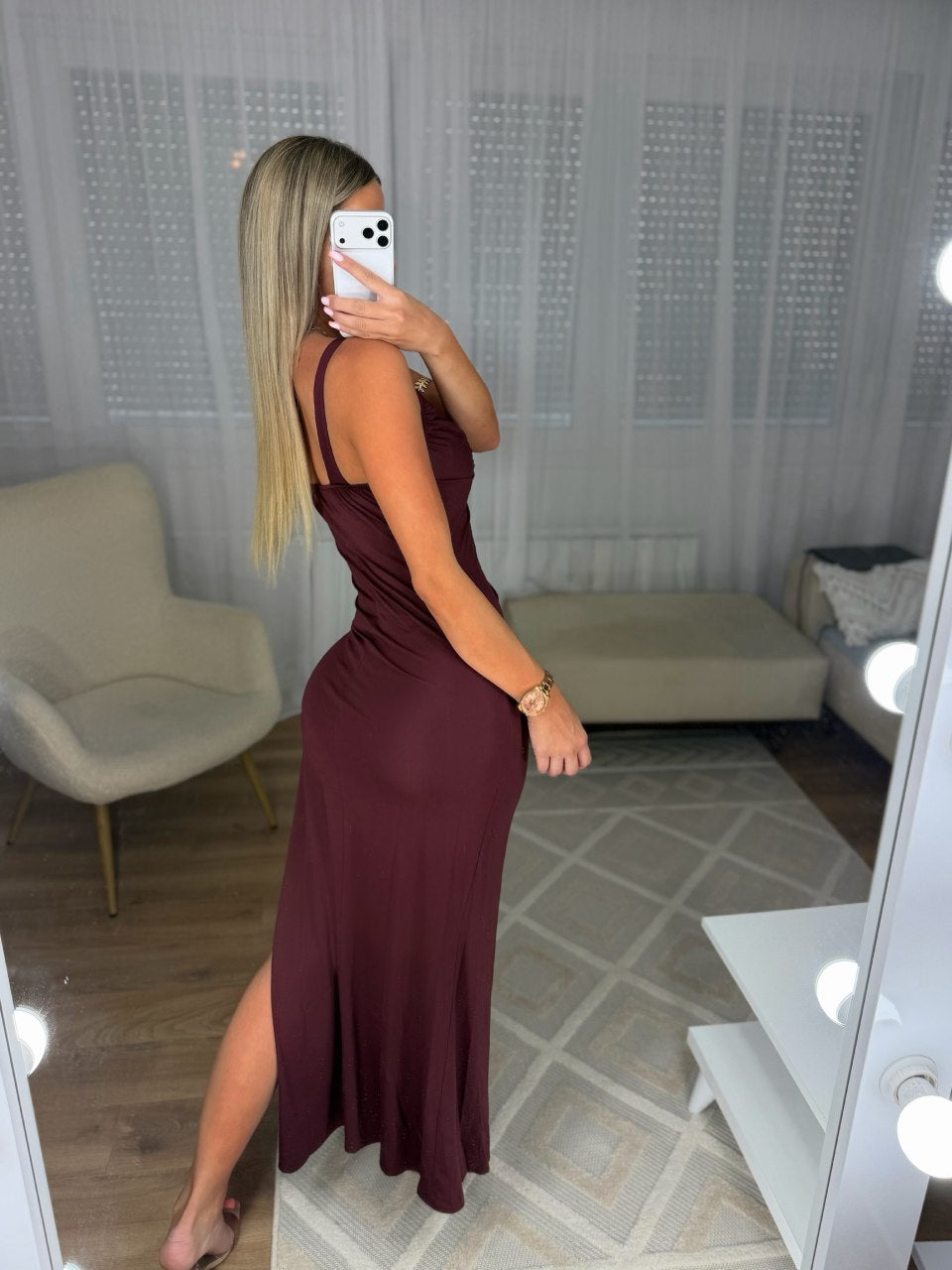 Captivate the room in this stunning burgundy maxi dress, designed to command attention at any upscale evening event. Crafted from a form-fitting, ruched fabric that hugs your curves, this dress features a striking sweetheart neckline accentuated by a bold metallic gold abstract hardware piece at the center. The sleek silhouette flows down into a dramatic floor-length finish with a high side slit, offering both glamour and effortless movement. Pair this showstopper with metallic statement accessories