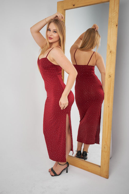 Woman in a red dress standing in front of a mirror on a plain background