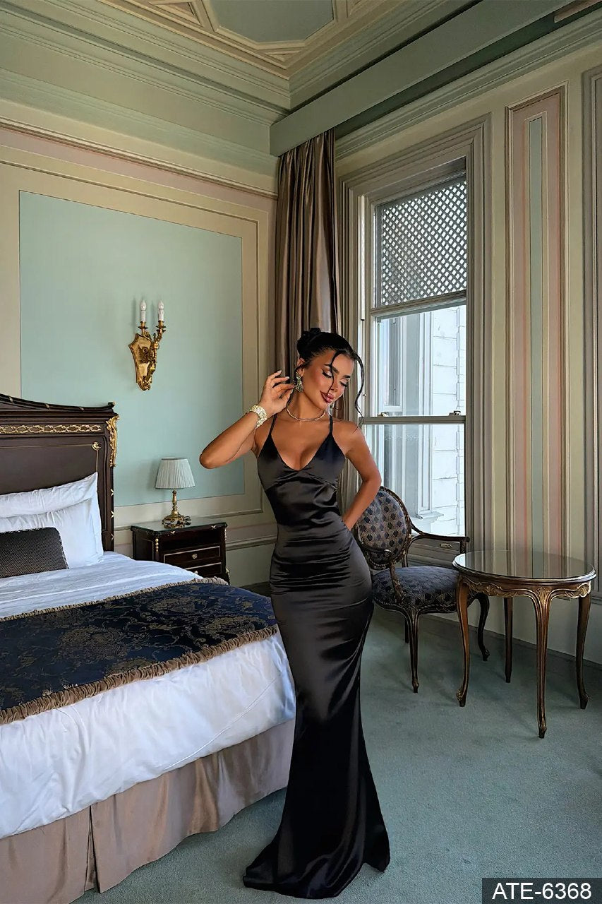 Elara black satin maxi dress with draped cowl neckline and fitted silhouette
Elara black satin open-back maxi dress with thin crossover straps
 Elara black satin maxi dress showing the low open back and slim straps